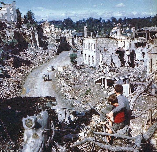 14. İki Fransız çocuk bir tepeden, Müttefik araçlarının yıkılmış olan binaların arasında geçişini izlerken, 1944.