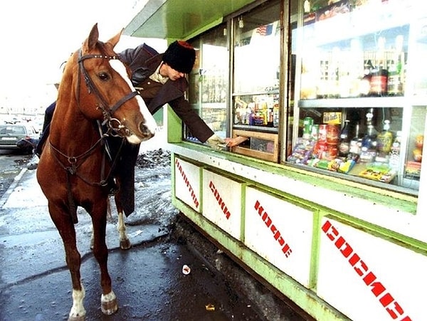 7. Казак на лошади покупает водку в киоске во время парада в честь Дня святого Патрика в Москве