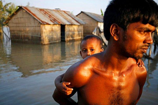 14. Bangladeş'in Bogra bölgesinde bir köyde baba ve oğul sel basan evlerinden uzaklaşmaya çalışıyor.