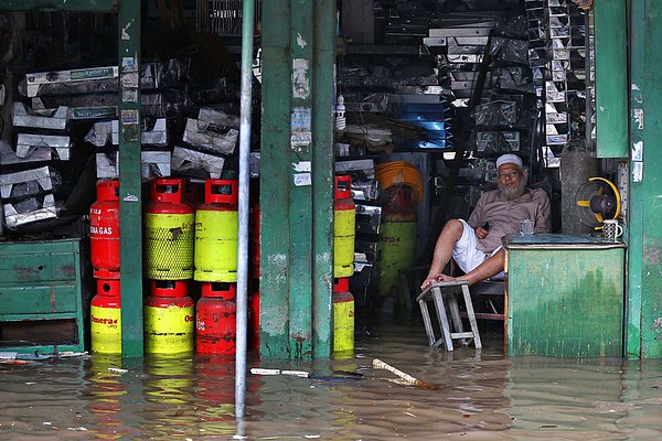 23. Dhaka'da Bangladeşli bir adam dükkanından yağmuru ve seli izliyor.