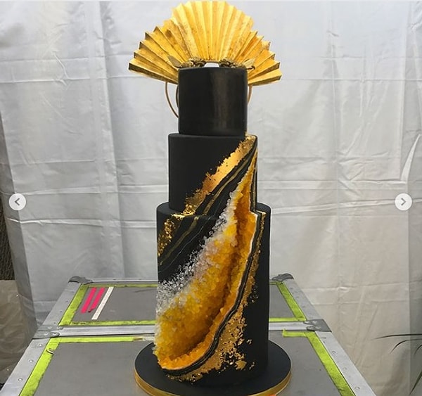 Медово-лавандовый трехуровневый десерт был покрыт черной помадкой и украшен кристаллами белого и желтого сахара.