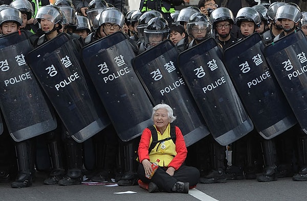 7. Seul'deki hükümet karşıtı protestocuları korumak için yolu kapatan polislerin önünde oturan kadın, 24 Nisan 2015