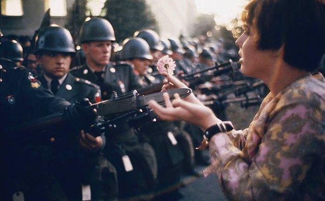10. ABD'nin Vietnam'da yürüttüğü savaşa karşı Pentagon'da yapılan protestoda genç pasifist Jan Rose Kasmir, kalabalığı hedef alan askerlere çiçek uzatıyor.