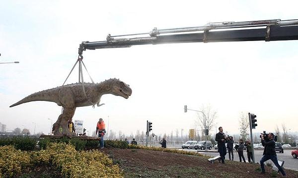 Vinç yardımıyla kaldırılan dinozor maketinin kaldırılma işlemlerini vatandaşlar ilgiyle izledi.