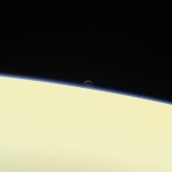 6. Satürn'ün aylarından biri olan Enceladus gezegenin ardında, Cassini uzay aracına poz vermiş gibi...