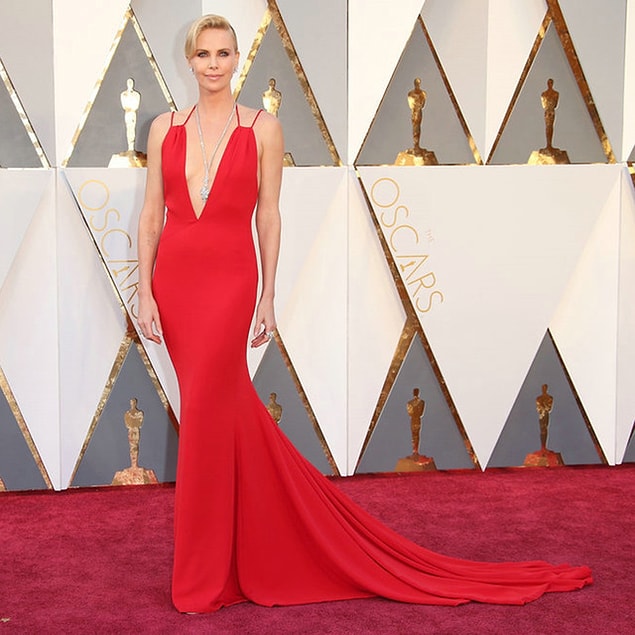 22. Charlize Theron derin bir göğüs dekolteli elbise ve dekoltesine doğru uzun parıltılı bir kolye tercih etmiş.