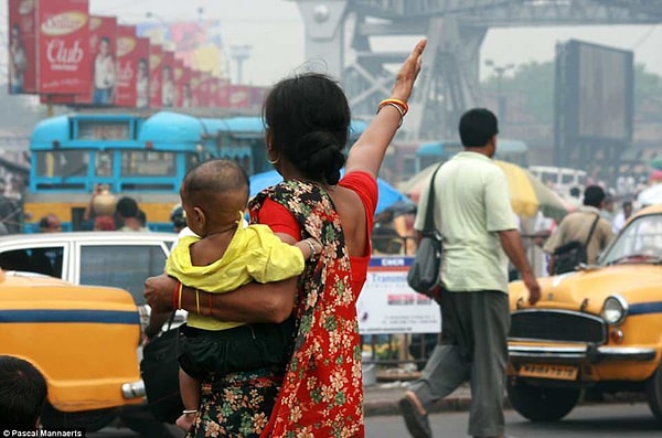 5. По словам фотографа, матери с радостью и гордостью позировали со своими отпрысками для снимков. Здесь мы можем видеть, как мама из Калькутты, Индия, ловит такси с сыном на руках (2013)