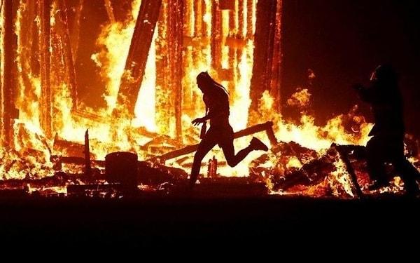 24. Burning Man Festivali’nde, yakılan ahşap kuklanın ortasına atlayan adam.