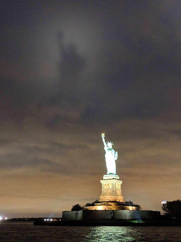 2. Özgürlük Heykeli'ni gece parlarken görmek çok da alışılmadık bir durum değil ama bulutlara yansıyan devasa gölgesi göz kamaştırıcı.