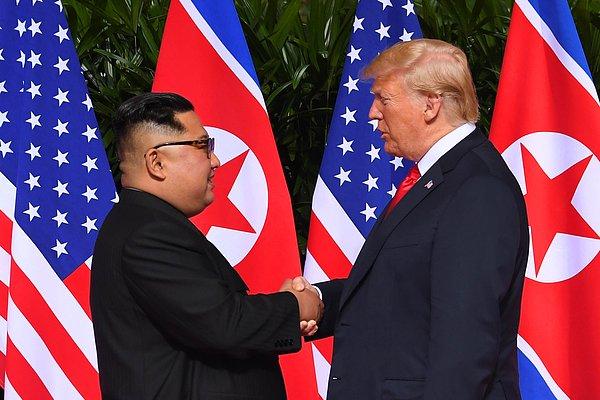 Trump ve Kim, ABD ile Kuzey Kore bayraklarının önüne kurulan kırmızı halıda birbirlerine doğru yürüdü, el sıkışarak poz verdi.