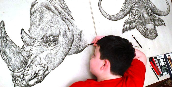Мальчик по памяти создаёт рисунки животных, прорисовывая при этом каждую мелкую деталь