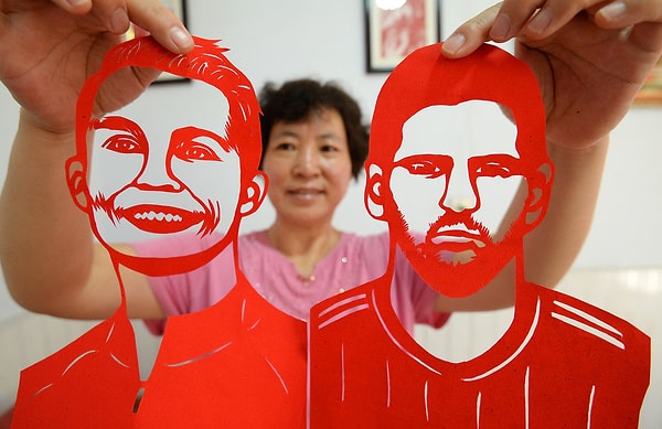 21. Народная художница Фенг Шипинг вырезает из бумаги лица одних из главных футбольных звезд - Лионеля Месси и Кришиану Роналду - 12 июня в городском округе Ханьдань, Китай.