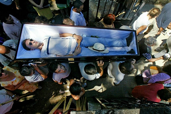 Комичность же ситуации заключается в том, что люди, у которых нет родственников, вынуждены нести свои гробы сами, периодически туда ложась и притворяясь мертвыми.