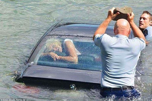 5. Polis, boğulmakta olan kadını kurtarmak için olan arabanın camını kırmaya çalışıyor.