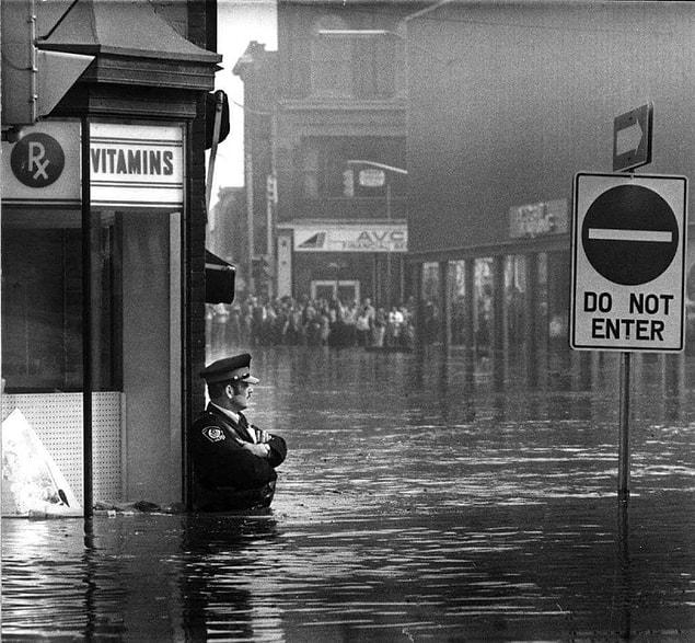 12. Police officer John Shuttleworth, waist-high in flood waters, Cambridge, Ontario, 1974