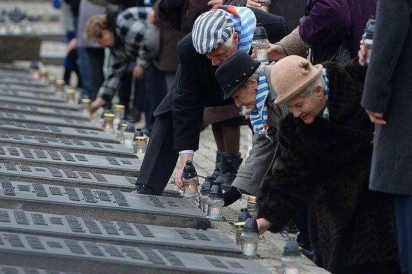 Auschwitz Kampı sağ kalanları, 27 Ocak 2016'da aileleriyle birlikte Oswiecim, Polonya'daki Kurbanlar Anıtı'na mum bırakıyor.