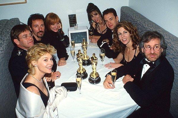 14. 21 Mart 1994 tarihli 66. Akademi Ödülleri'ni takiben, Elton John AIDS Vakfı partisindeki (saat yönünde soldan) Kate Capshaw, Elton John, Bruce Springsteen, Patti Scialfa, Tom Hanks, Rita Wilson ve Steven Spielberg.