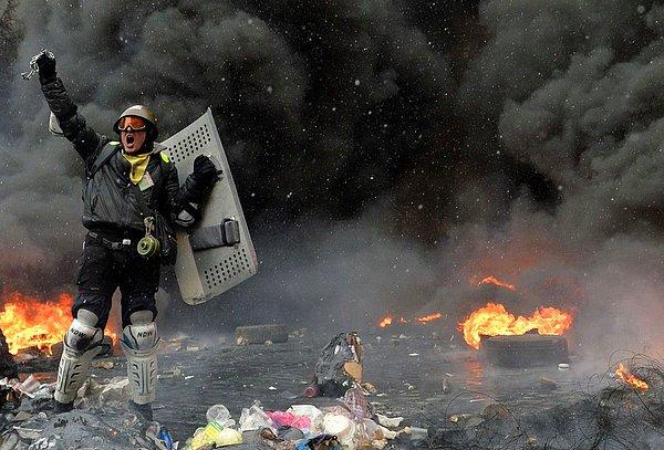 4. Bir gösterici Kiev'de yanan lastiklerin ve çöplerin arasında duruyor.
