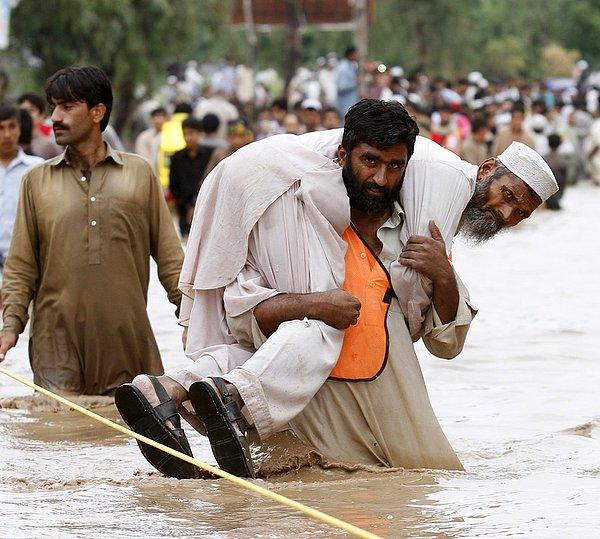 19. Pakistan'da yaşanan tufan sırasında babasını sırtında taşıyan adam...