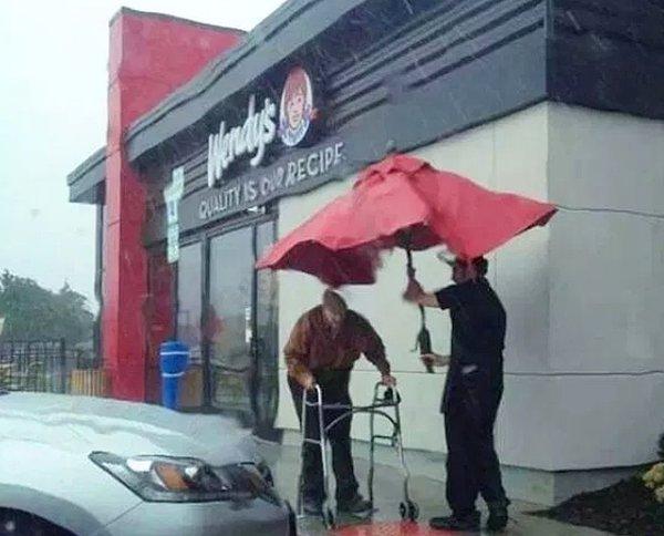 25. Yaşlı müşterilerine masa şemsiyesiyle yardım eden bir Wendy's çalışanı...