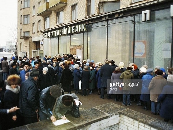 14. Люди стоят в длинной очереди, чтобы положить деньги на счёт в Сбербанке.