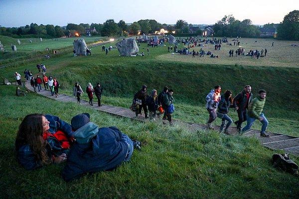 3. İnsanlar Wiltshire'deki Avebury anıtının manzarası eşliğinde gün doğumunu seyretmek için yerlerini almaya hazırlanıyorlar.