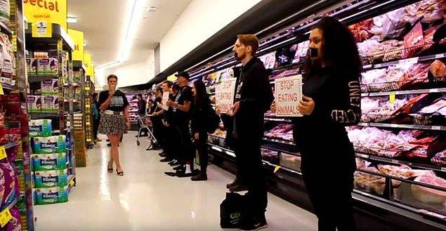 Et almak için markete gelen müşterilerin önüne barikat kuran veganlar, ellerindeki dövizlerle insanları et ürünlerinden uzak tutmaya çalıştı.