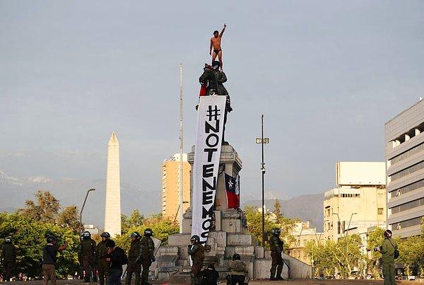 Plaza Baquedano'daki bir gösterici, bir anıtın üstünde duruyor: “Korkmuyoruz”