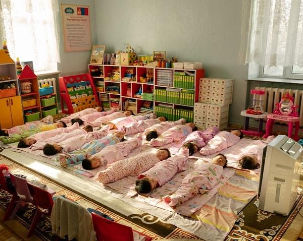 22. Moğolistan'daki bir kreşte hava temizleyici makinenin yanında uyuyan çocuklar, Matthieu Paley imzalı fotoğraf.