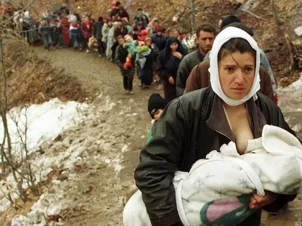 39. Kosova'daki savaşla evlerinden olan 2000 diğer mülteciyle yürüyen Arnavut kadın, bebeğini emziriyor. Yıl 1999.