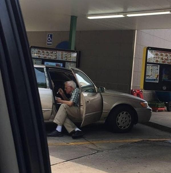 14. Yaşlı bir amca, arabanın kenarına oturarak eşine dondurma yediriyor.