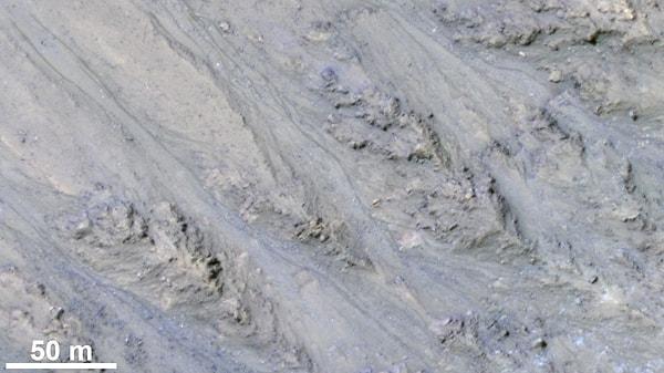 Mars yüzeyindeki bir kraterin iç yamacında, muhtemelen eski su yollarının geride bıraktığı bir kalıntı olan kum akıntıları: