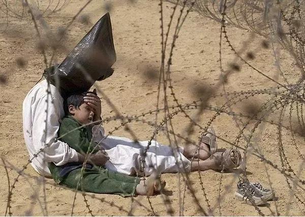 6. Iraklı savaş mahkumu, oğlunu sakinleştirmeye çalışıyor.