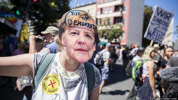 Koronavirüs tedbirlerin eleştirildiği döviz ve pankartlar taşıyan göstericiler, Almanya Başbakanı Angela Merkel ve Sağlık Bakanı Jens Spahn aleyhine sloganlar attı.