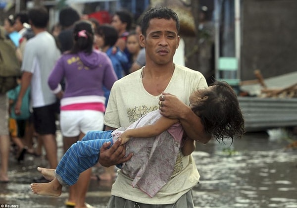 11. Отец несет безжизненное тело дочери после тайфуна.