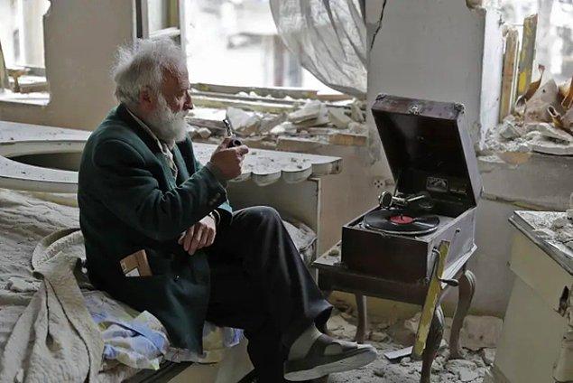 14. 70 yaşındaki Suriyeli adam, evinin yıkıntıları içinde oturuyor.