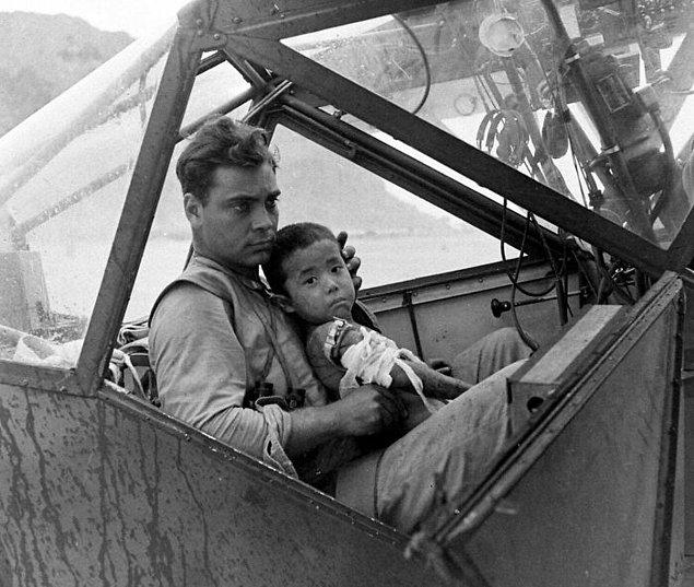 8. Saipan Savaşı'nda, yaralanan Japon çocuğu hastaneye götürmek için uçağın kokpitinde bekleyen Amerikan askeri. (1944)
