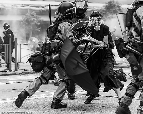 Протестующий в противогазе, очках и под зонтиком во время столкновения со специальным подразделением в Гонконге. Путешествующий документальный фотограф и фотограф-натуралист Вей Фу из Канады получил почетную награду за этот потрясающий снимок в категории любительской фотожурналистики.
