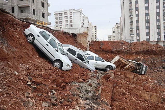 Binanın bahçesinde bulunan 6 araç, yan tarafta bulunan bir inşaatın temeli için kazılan yere düştü.