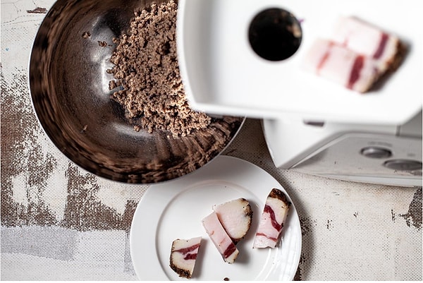 6. Чтобы получить нежную начинку, измельчите мясо и лук вместе с ветчиной в комбайне. Добавьте специи и один зубчик раздавленного чеснока и снова обжарьте на сковороде 2 минуты.