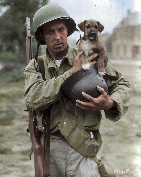 20. Pfc Joseph E. Day (1918-2009), Alman miğferinde Invasion isimli yavru bir köpeği tutarken (Le Dezert, Fransa, 1944).