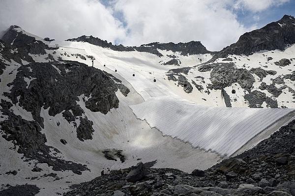 Kayak sezonu sona erdiğinde, bilim insanları güneş ışınlarını engelleyen beyaz bir muşamba kullanarak buzuldaki erimeyi durdurmaya çalışıyorlar.