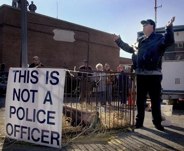 Bir polis memuruna 'domuz' diyen adam, sokağın köşesinde bir domuzla beraber 'bu bir polis değildir' pankartı taşıdı.