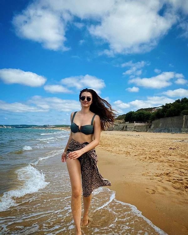 Sırada geçen senenin yazından tatlı bir fotoğraf var. Burcu Özberk, bikinisi ve gözlüğüyle deniz kenarında eğleniyor.