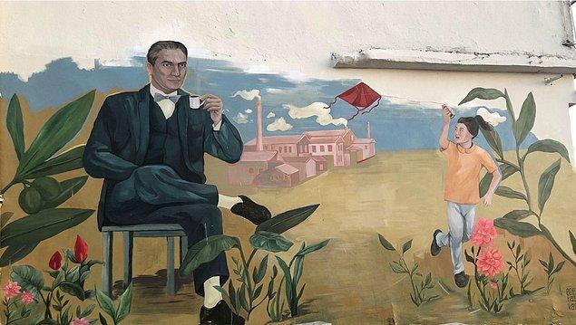 "Ayvalık ve Balıkesir'in doğal güzelliği ve kültürel birikimine ait unsurları içeren resimlerde Mustafa Kemal Atatürk Zeytin yaprakları içinde Türk kahvesini yudumlarken kalkınan Ayvalık silüeti önünde umudu temsil eden kız çocuğu uçurtma uçuruyor."