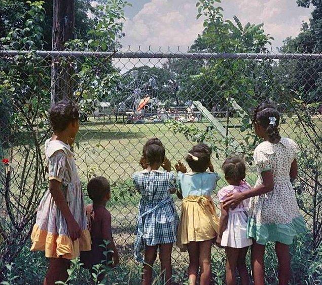 18. Kendilerinin girmesinin yasak olduğu, yalnızca beyaz Amerikalılara ayrılmış çocuk parkını uzaktan izleyen Afroamerikalı çocuklar...