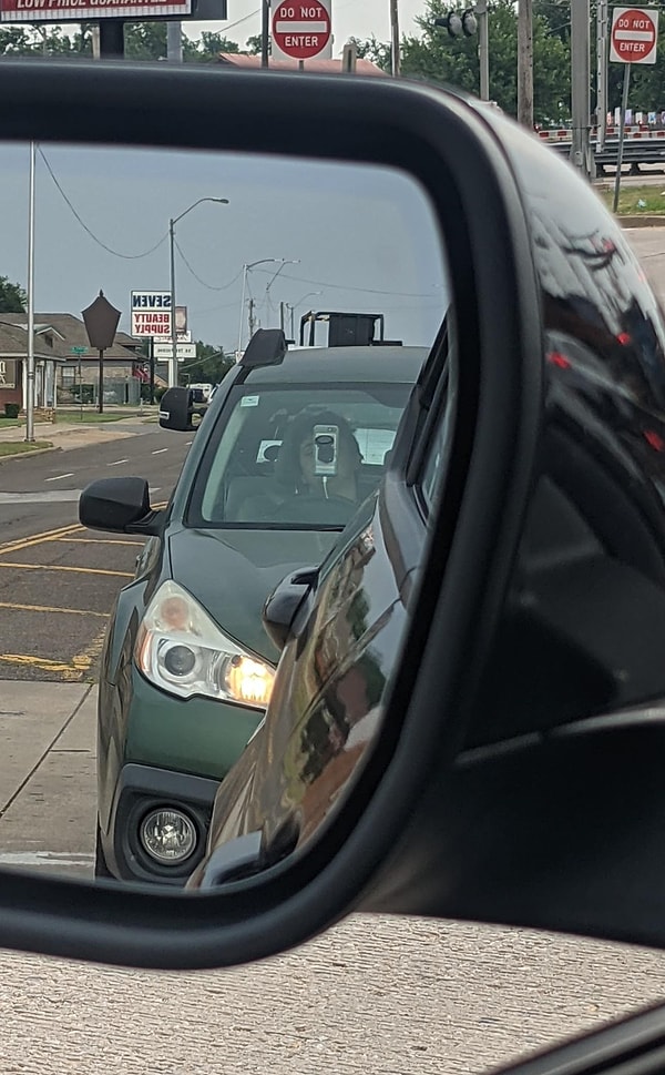 17. Человек за рулем с большим старым телефоном, закрывающим всю видимость: