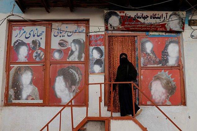 96. Afganistan'ın başkenti Kabil'de peçe takan bir kadın, kadın fotoğraflarında yüzlerin silindiği bir güzellik salonuna giriyor, Jorge Silva.