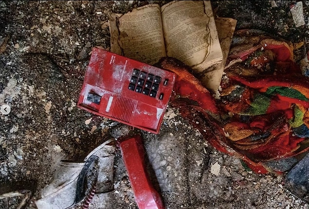 Geneleve ait eski bir telefon, topuklu terlik ve bir kitap aynı karede