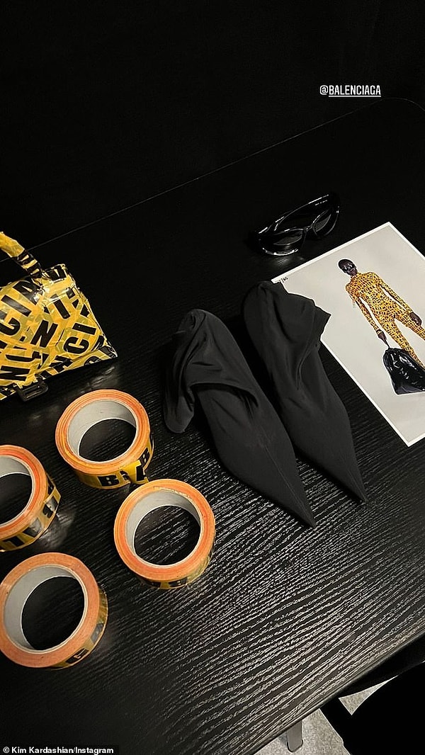 Ким также включила снимок, на котором рулоны ленты были размещены на столе рядом с сумкой Balenciaga Hourglass, которая также была почти полностью покрыта лентой. На другом изображении солнцезащитные очки Balenciaga и туфли на каблуках телеведущей были замечены рядом с визуализацией ансамбля с предупредительной лентой.